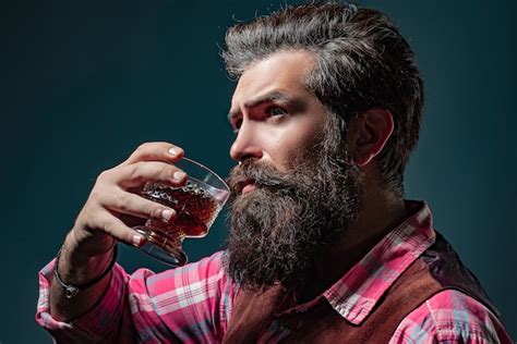 Premium Photo Man Bartender With Beard Holds Glass Brandy Sommelier