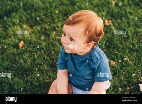 Outdoor Portrait Of Adorable Redheaded Baby Boy Playing In Summer Parc