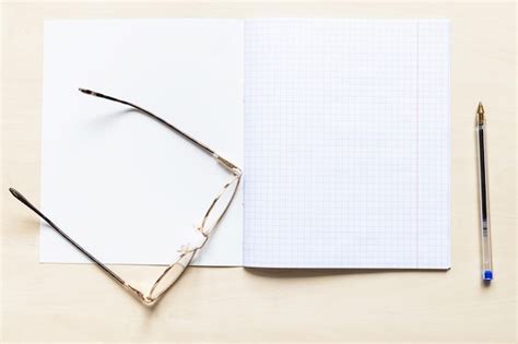 Caneta e óculos no caderno de escola aberta em branco Foto Premium