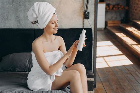 Girl Wrapped In Towels Uses Sunscreen Lotion After Shower Sitting On Bed In Hotel Body Skin