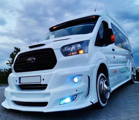 A White Ford Transit Van Parked On Top Of A Brick Road