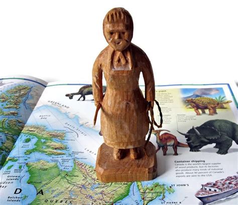 A Wooden Figurine Sitting On Top Of An Open Book Next To A Map