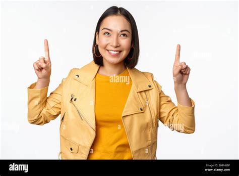 Image Of Smiling Asian Brunette Woman Pointing Fingers Up Showing Advertisement With Happy Face