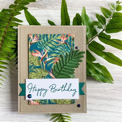 A Happy Birthday Card With Tropical Leaves And Greenery On The Table