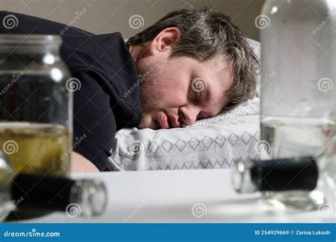 A Drunken Alcoholic Man Lies On The Bed Empty Bottles On The Table