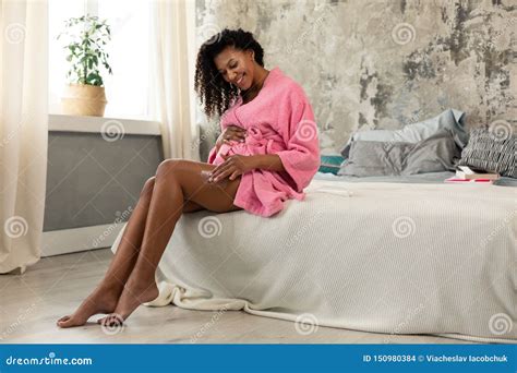 Smiling Pregnant Woman Spreading Cream On Her Legs Stock Photo Image