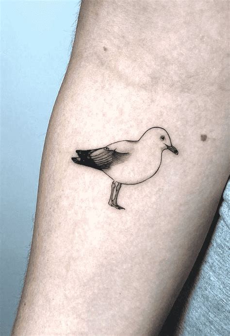 a small black and white bird tattoo on the right arm, with an outline of a seagull