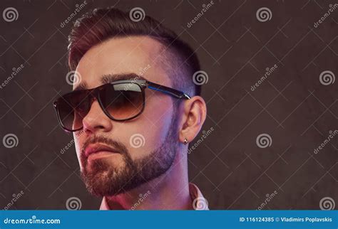 Close Up Portrait Of A Confident Stylish Bearded Man With Hairstyle And Sunglasses In A Gray