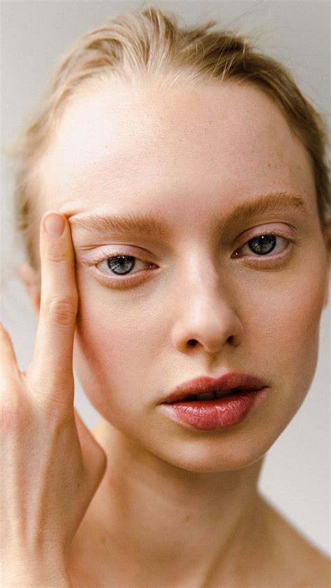 A Woman Holding Her Hand Up To Her Face With One Eye Open And The Other