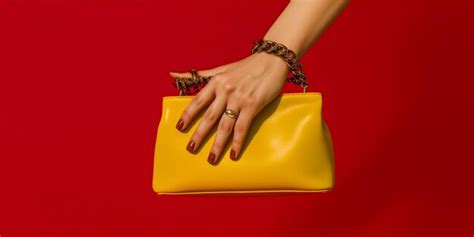 Premium Ai Image Hand Holding A Leather Handbag On A Red Background