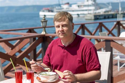 Premium Photo An Adult Blonde Man Has Lunch On The Beach In A Cafe