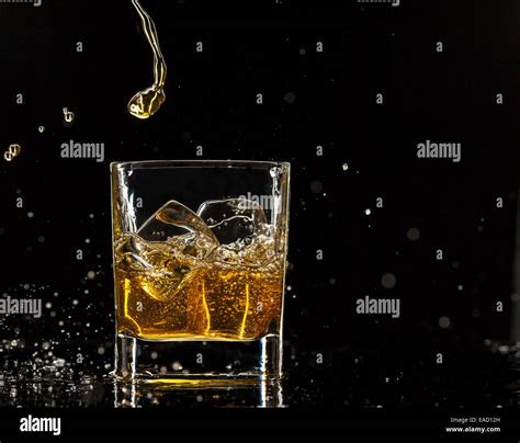 Pouring Whiskey Into Glass Isolated On Black Background Stock Photo