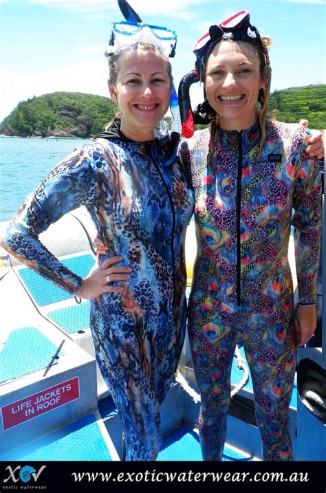 Two Women In Wetsuits Standing On The Back Of A Boat