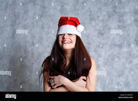 Attractive Years Brunette Smiling Topless Woman In Santa Hat Studio On Grey Stock Photo
