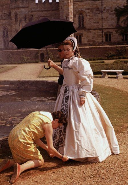 Two Women Dressed In Period Clothing One Holding An Umbrella And The