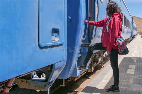 Side Profile Of A Female Tourist Embarking A Blue Train Carriage