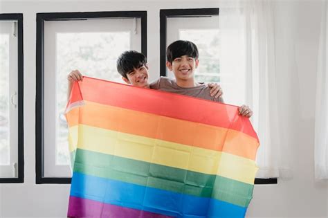 Portrait de jeune couple gay asiatique se sentir heureux montrant le drapeau arc en ciel à la