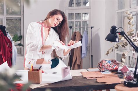 La diseñadora de moda femenina que trabaja en el estudio sentado en el