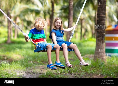 Kids On Swing Children Swinging On Playground In Tropical Resort With