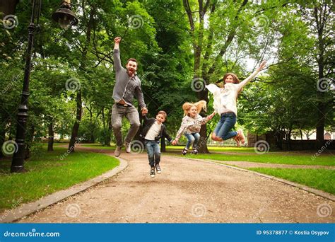 La Familia Feliz Alegre En El Parque Del Verano Junta Que Salta Se