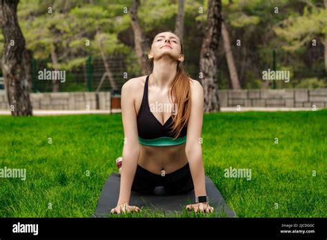 Cute Brunette Woman Wearing Sports Bra Standing On City Park Outdoors Doing Yoga Stretching On