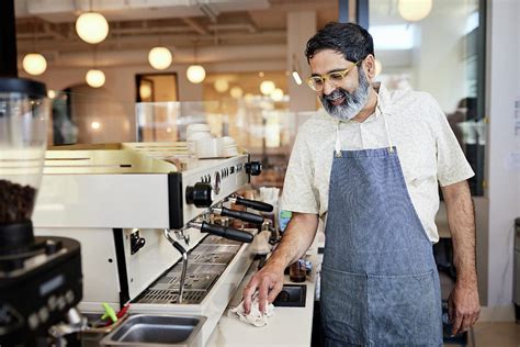 Smiling Mature Male Entrepreneur Cleaning Kitchen Counter In Cafe