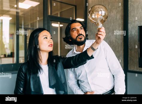 Mature Business Colleagues Analyzing Light Bulb At Office Stock Photo