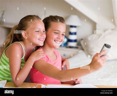 Young Girls Distracted From Their Homework Playing With A Cellphone