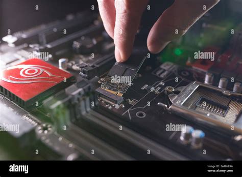 Focus at SSD slot, type M.2 with support for NVMe, on computer motherboard. Technician is ...