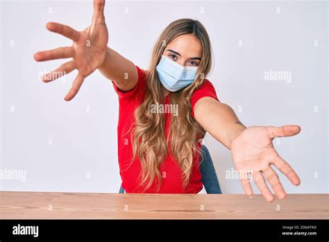 Jeune Belle Femme Blonde Portant Un Masque M Dical Assis Sur La Table Regardant La Cam Ra