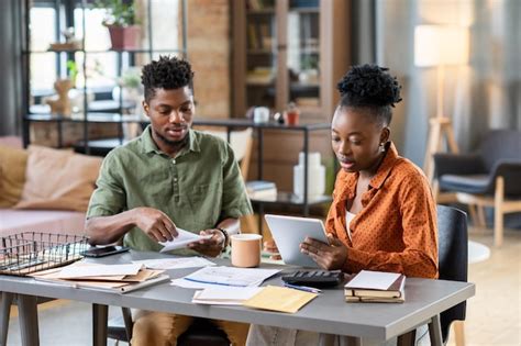 Premium Photo Concentrated Young African American Couple Sitting At Table With Bills And