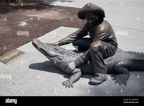 bronze man sitting on alligator sculptures in heritage square park city ...