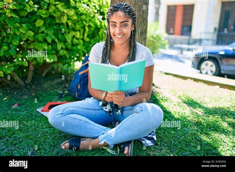 Young African American Student Woman Reading A Book Sitting On The