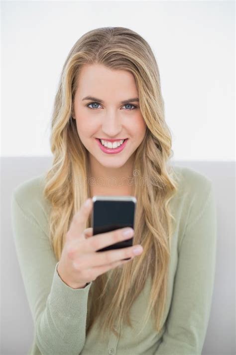 Cheerful Pretty Blonde Sending A Text Sitting On Cosy Sofa Stock Image