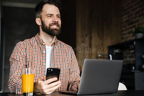 Happy Mid Aged Brunette Bearded Man Sitting At The Table Stock Photo
