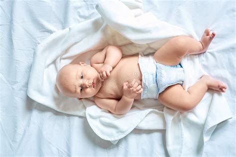 Little Baby In Diaper Lying On Bed At Home Looking Aside Concerned Top