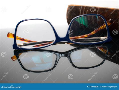 Antique Book And Reading Glasses On A Reflective Surface Stock Image