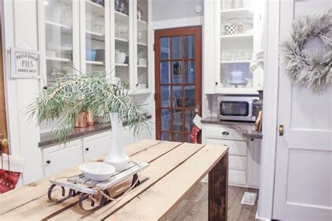 A Wooden Table With A Potted Plant On Top Of It In Front Of A White Kitchen