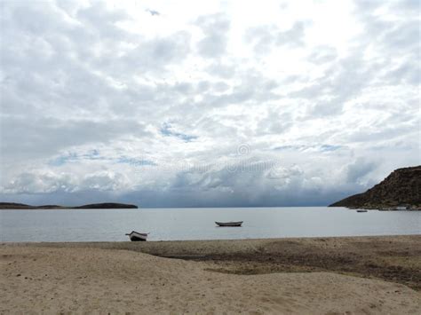 Clouded View To A Lake Beach In Bolivia With Boats In Front Stock Photo