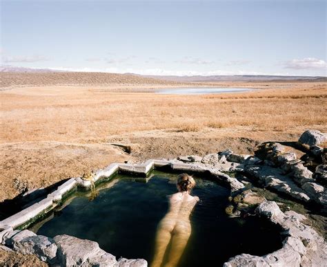 A Person Standing In The Middle Of A Body Of Water Surrounded By Rocks