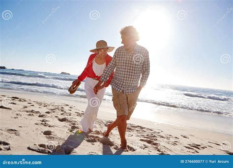 Holdiay Happiness A Mature Couple Enjoying A Late Afternoon Walk On The Beach Stock Image