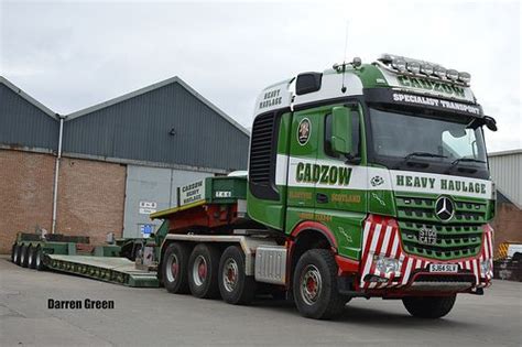 A Green And White Semi Truck Parked In Front Of A Building