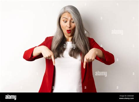 Impressed Asian Mature Woman Checking Out Promo Pointing And Looking Down With Amazed Face