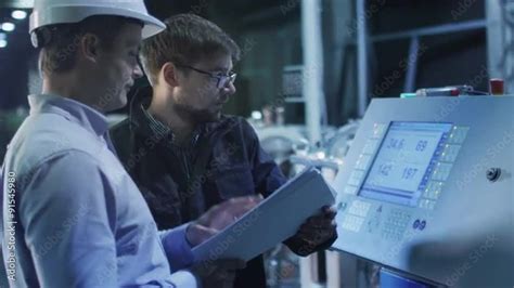 Engineer And Factory Worker Are Setting Up CNC Lathe Machine Together