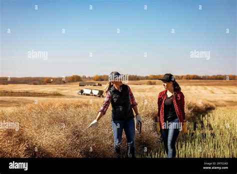 Una agricultora de pie en los campos enseñando a su aprendiz sobre