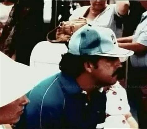 A Man With A Baseball Cap On Sitting Next To Other People