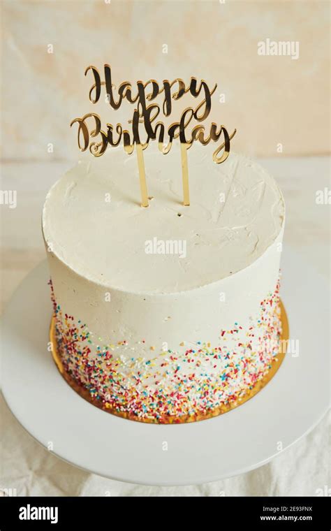 Vertical shot of a cake with a ''happy birthday'' cake topper and sprinkles on a tray Stock ...