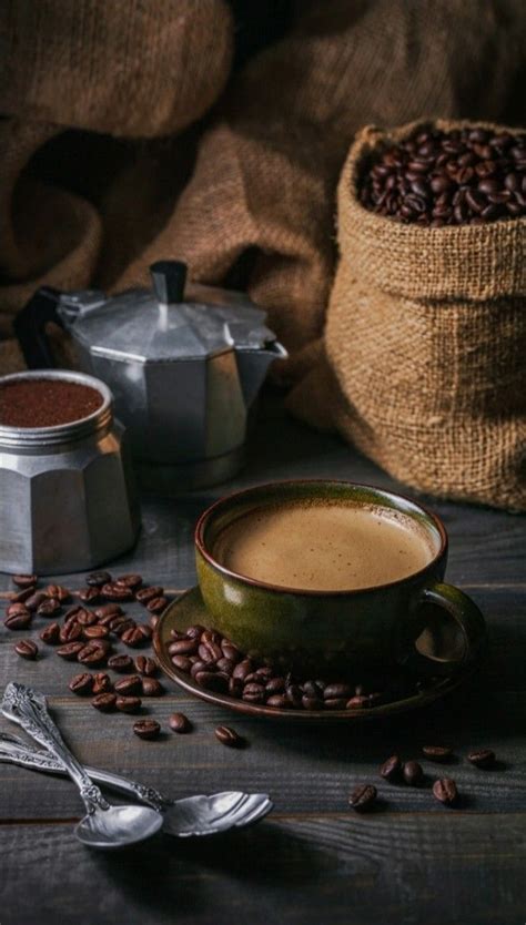 A Cup Of Coffee Sitting On Top Of A Saucer Next To Some Beans And A Bag