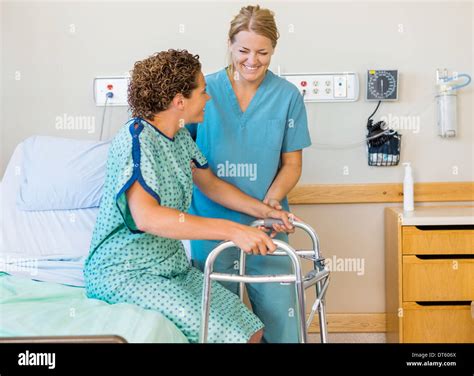 Nurse Assisting Patient Using Walking Frame In Hospital Stock Photo