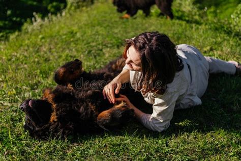 Mujer Y Tibetano Perro Mastiff Tendido Sobre La Hierba Y Jugando Juntos